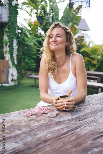 Smiling woman sitting at wooden table in park