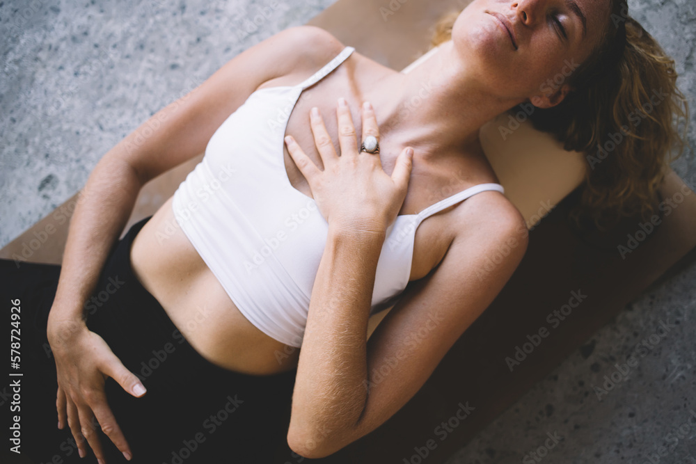 Young crop woman lying on marble floor with eyes closed
