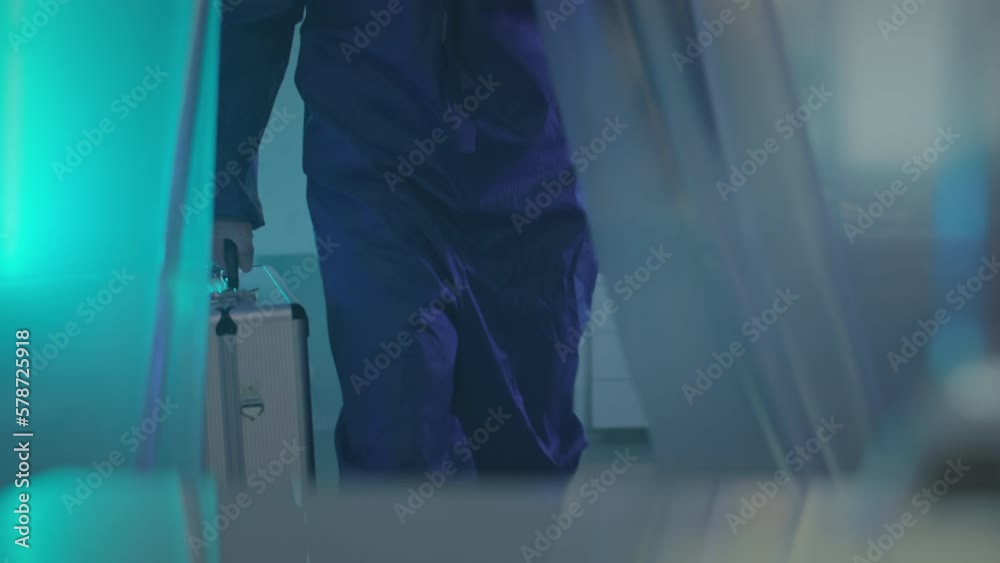 Slowmo of biotechnologist in protective clothing carrying silver suitcase while inspecting secret laboratory