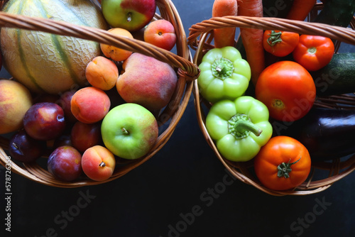 Two wickers baskets with healthy seasonal fruit nad vegetable. Dark background  top view.