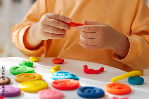 A little girl playing with colorful pieces of plasticine. Art Activity for Kids. Fine motor skills, creativity and hobby. Sensory play for toddlers.
