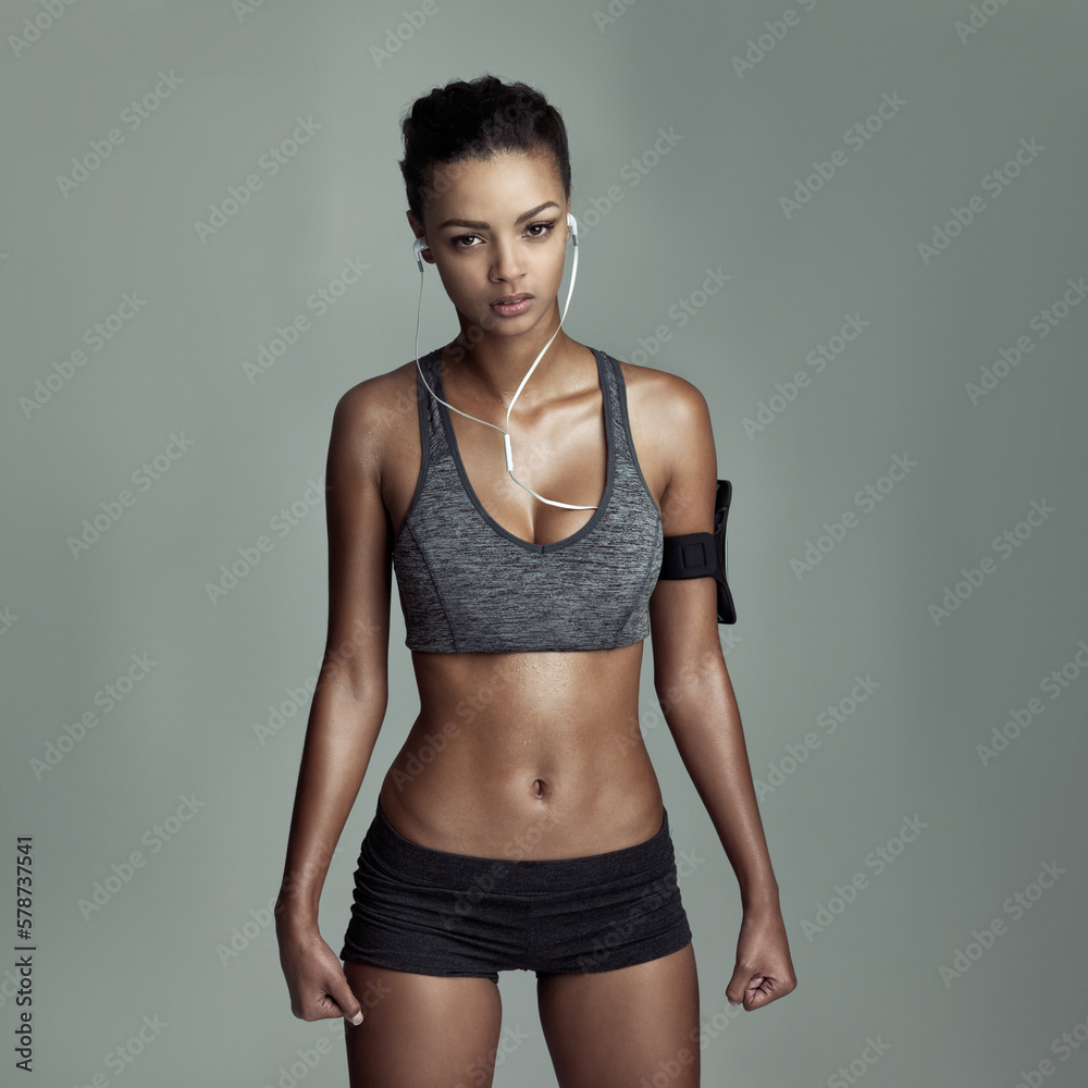 Always up for a fitness challenge. Studio shot of a fit young woman listening to music against a gray background. Always up for a fitness challenge. Studio shot of a fit young woman listening to music against a gray background.