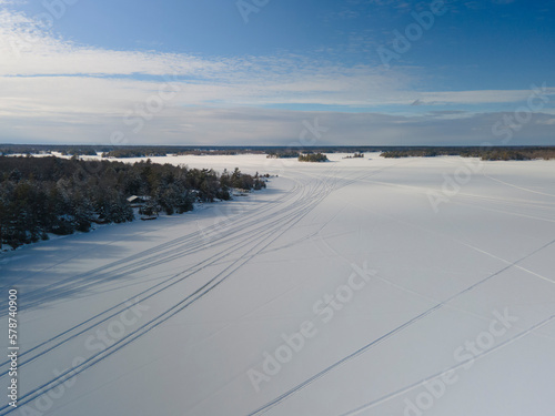 Winter scene - snowmobile tracks on frozen lake covered with snow. Winter outdoor activities concept.