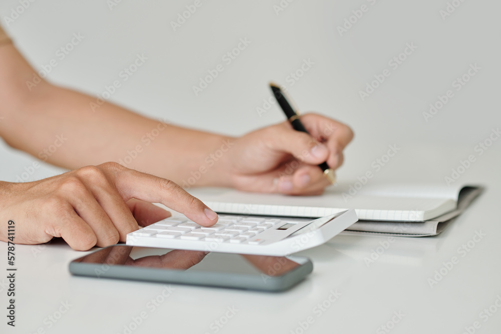 Fototapeta premium Hands of businessman making calculations and taking notes in planner