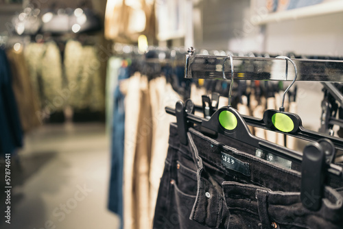 Close-up image of a hanger holding black jeans hanging inside a clothing store.