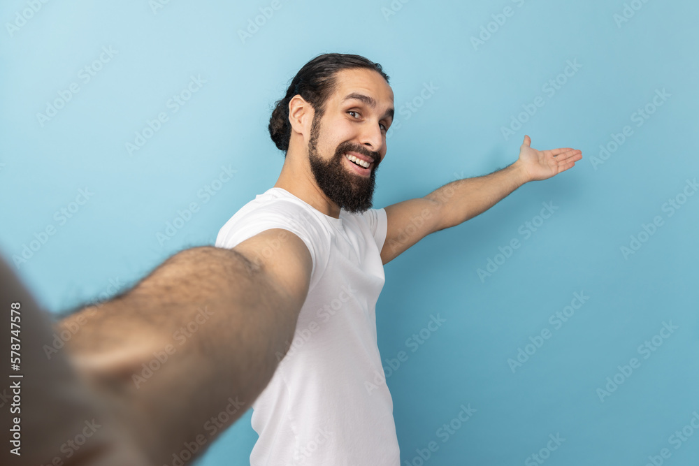 Man looking at camera with smile, making welcome gesture, taking selfie POV. Man looking at camera with smile, making welcome gesture, taking selfie POV.
