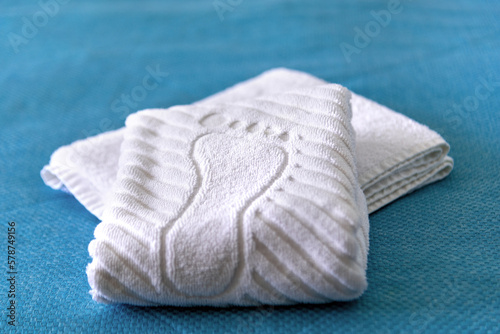 A stack Clean white bath towels lying on bed in hotel suite, close-up and selective focus