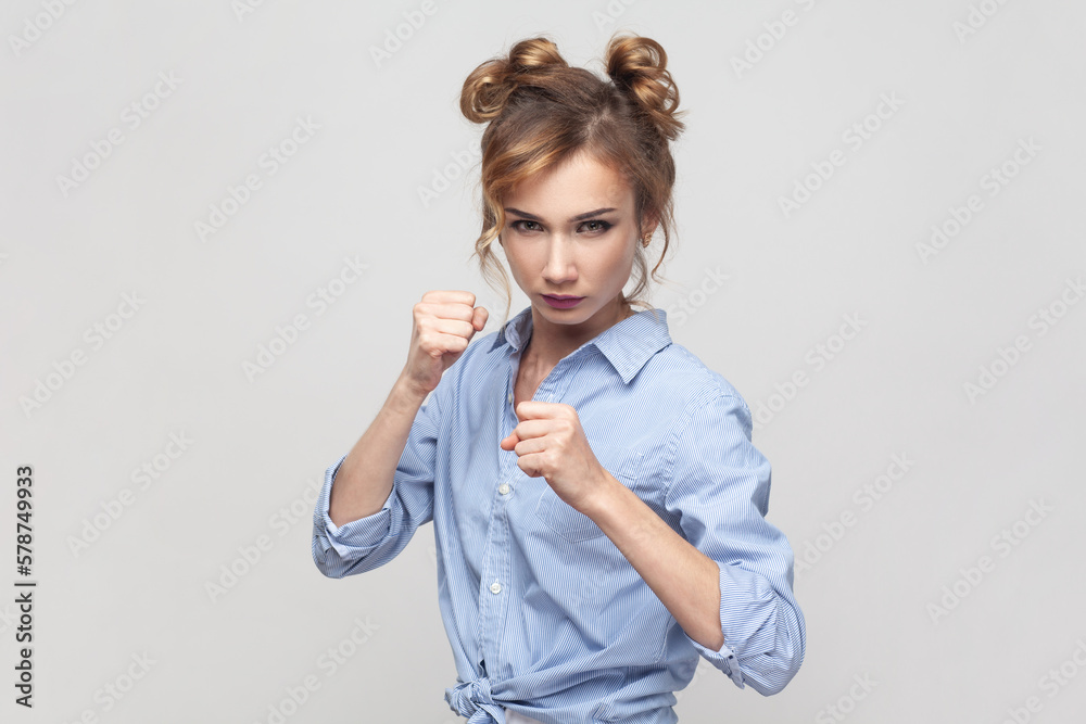 Woman having serious and confident look keeping fists clenched in front of her defencing herself.