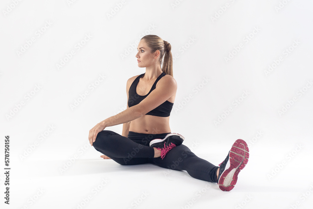 Attractive athletic blonde woman sitting on floor and stretching her body before work out. Attractive athletic blonde woman sitting on floor and stretching her body before work out.