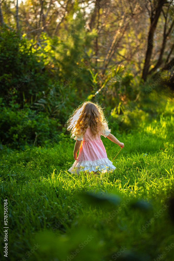 Little girl in a dress playing at the woods.