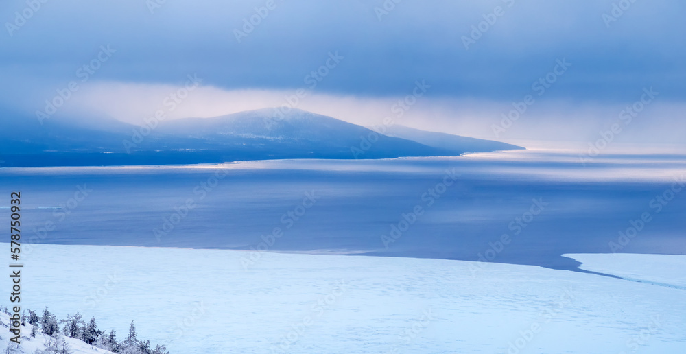 Panoramic view of beautiful winter seascape. Ice-covered seashore and unfrozen water. Ice floes on the coast. Landscape with sea coast. Cold weather. Harsh northern nature. Journey to the Far North.