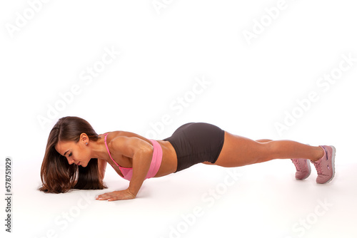 Close-up of a beautiful fitness girl in a sports top doing push-ups. Workout at home. Simple sports exercises for everyone