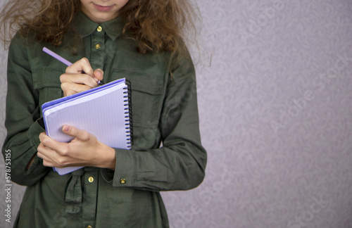 Close-up of a teenage girl making zebras and writing by hand with a pencil in a notebook.