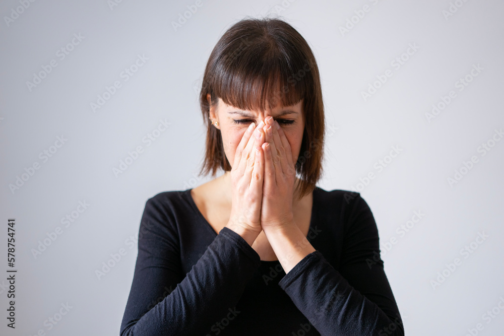 Portrait of a girl on white background. Brown short hair girl. Girl covering her face with her clasped hands, we only see her eyes. Portrait of a girl on white background. Brown short hair girl. Girl covering her face with her clasped hands, we only see her eyes.