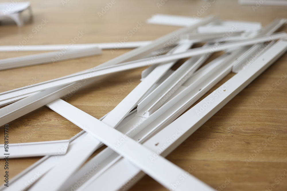 Many white plastic cable trays on wooden floor close up.