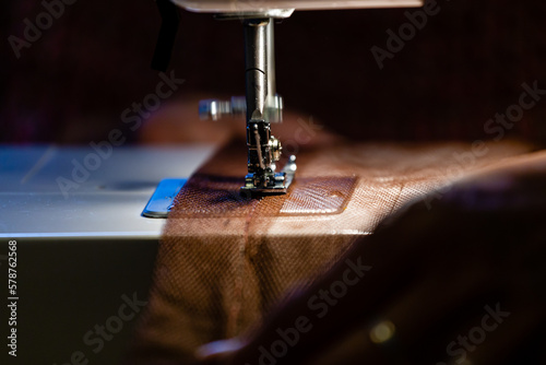 Schilderij op canvas maquina de coser cosiendo una tela de color marrón con poca luz