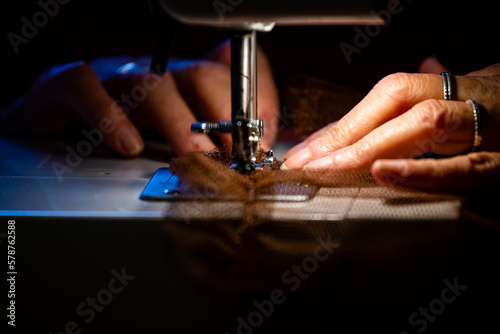 Manos enhebrando el hilo en una máquina de coser