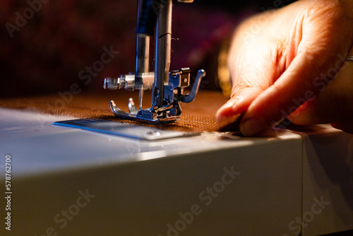 Manos enhebrando el hilo en una máquina de coser