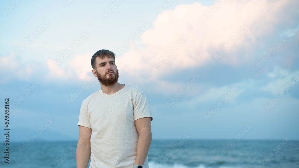 Serious young man on the beach, summer sea with beard Serious young man on the beach, summer sea with beard