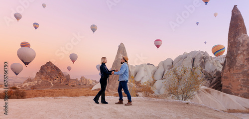 Loving couple hugging against background of hot air colorful balloons, romantic honeymoon in Cappadocia Turkey. Banner Travel photo tourist photo
