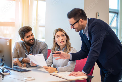 Business people discussing an agenda document containing topics, action items, and activities of their organization during the meeting.