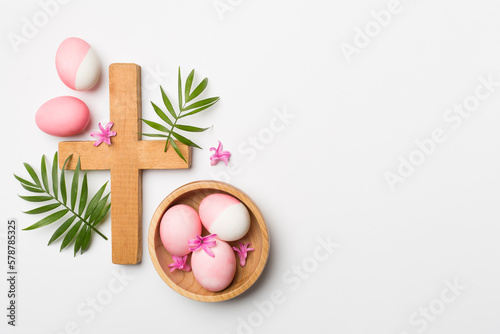Photography Pink Easter eggs with cross and palm leaves on color background, top view