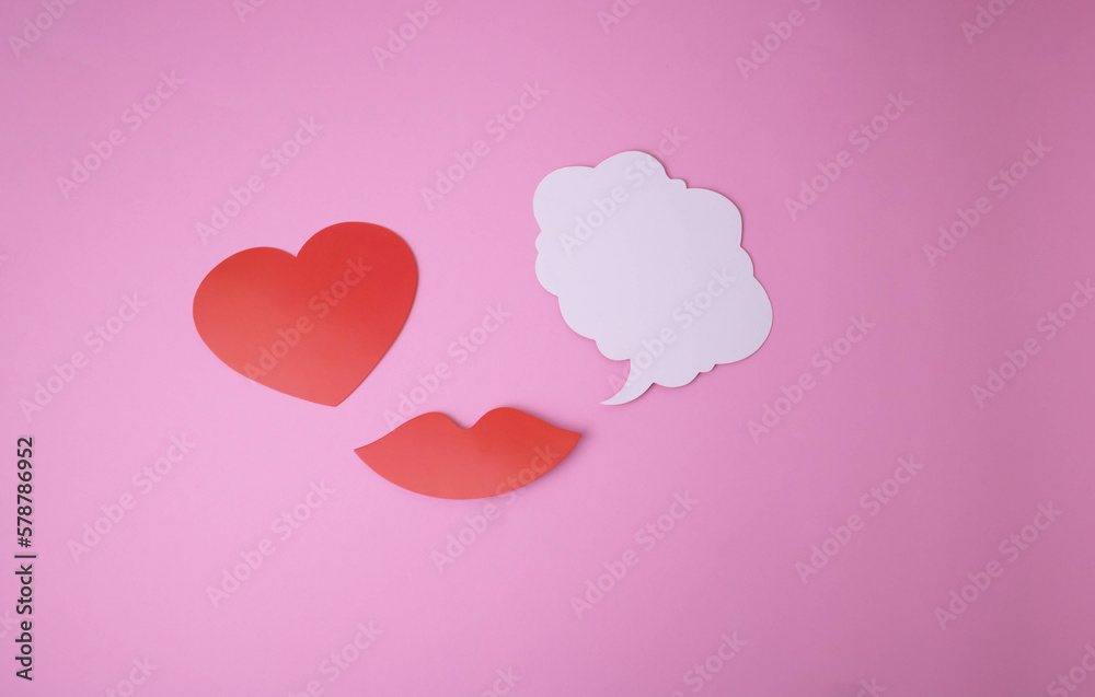 On a pink background paper red lips and a heart and a white cloud for words