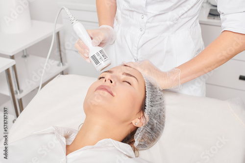 Beautician makes cryotherapy for rejuvenation woman face, anti aging cosmetic procedure with in beauty spa salon. Cosmetologist makes cryo therapy lifting with for skin rejuvenation and smoothing photo