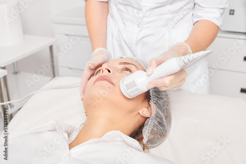Canvastavla Beautician makes cryotherapy for rejuvenation woman face, anti aging cosmetic procedure with in beauty spa salon