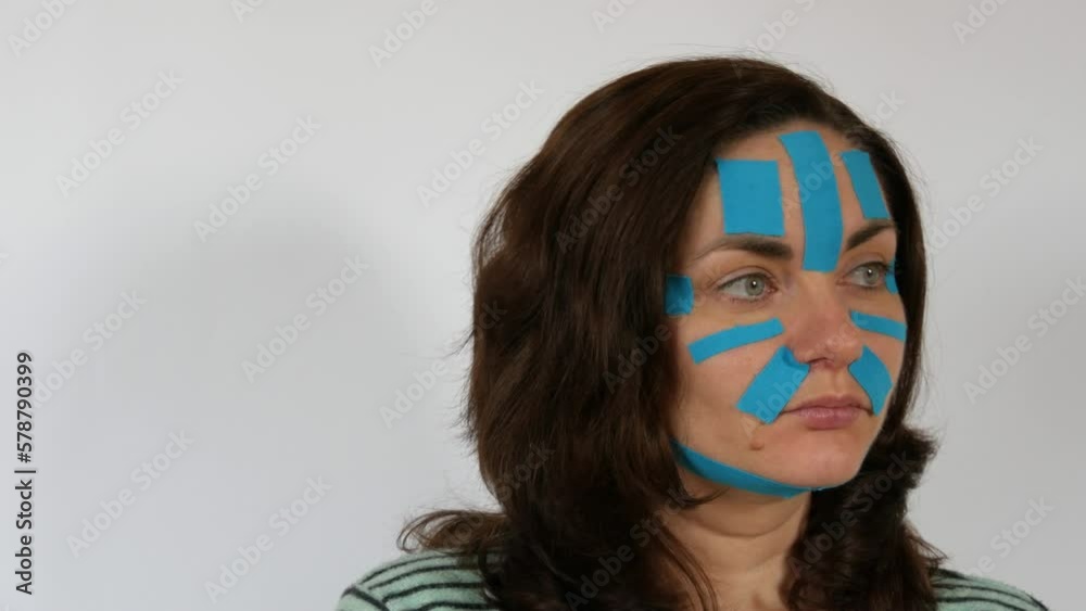 Young woman applied light blue kinesio strips taping face, forehead