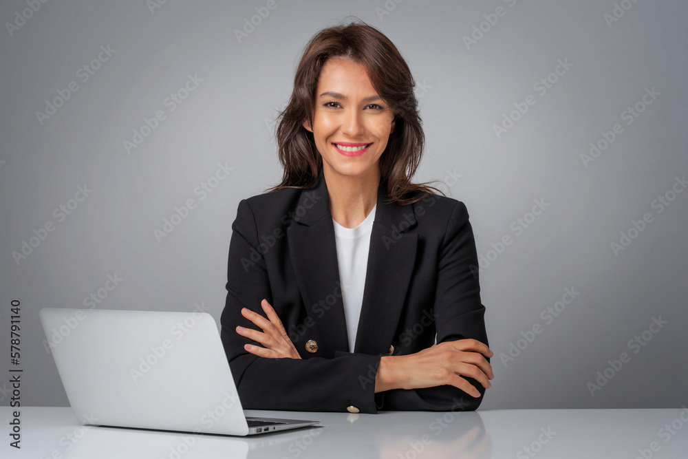 Studio portrait of an attractive mid aged businesswoman with laptop sitting at isolated bacgkround Studio portrait of an attractive mid aged businesswoman with laptop sitting at isolated bacgkround