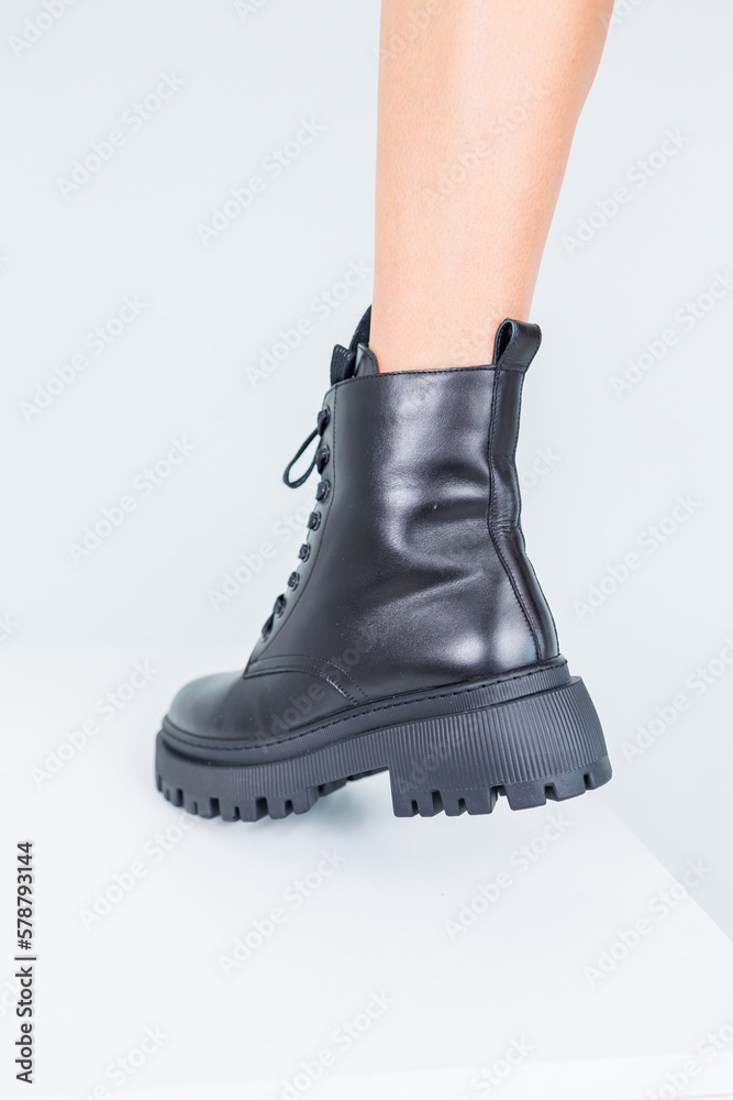 Close-up of female legs in black leather lace-up boots. Women's comfortable spring casual shoes. Black women's spring boots Close-up of female legs in black leather lace-up boots. Women's comfortable spring casual shoes. Black women's spring boots