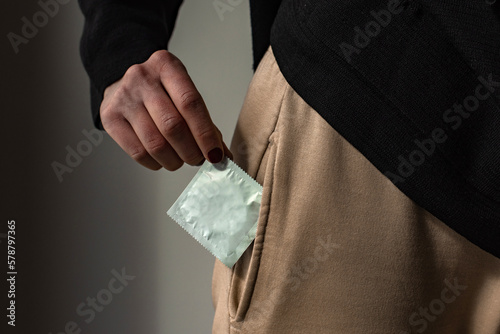 Detalle de una mujer poniendo un condón dentro del bolsillo de sus pantalones. Concepto de sexo seguro. Protección contra embarazos y enfermedades de transmisión sexual. Métodos anticonceptivos.