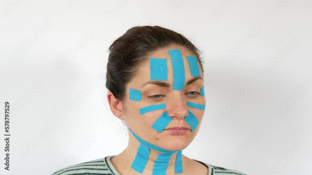 Vidéo Stock Young woman applied light blue kinesio strips taping face