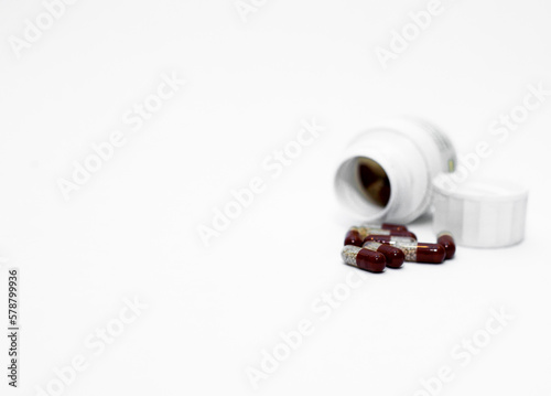 Bottle and scattered tablets on light-coloured background, top view. Space for text