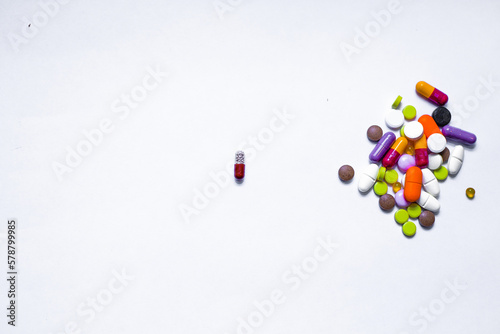 Bottle and scattered tablets on light-coloured background, top view. Space for text