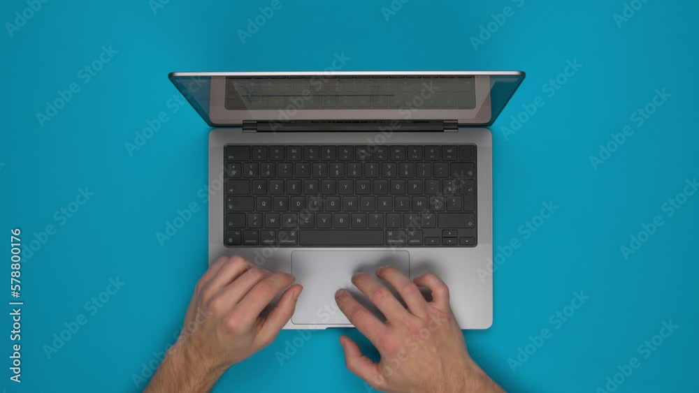 Vue de dessus d'une personne utilisant un ordinateur portable sur un fond bleu uni