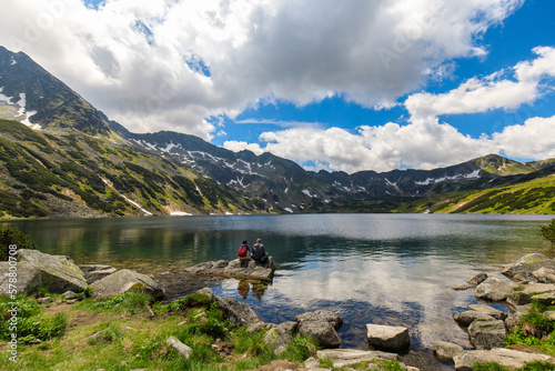 Couple of tourists sitting on a rock in the Valley of five ponds in the Polish Tatras