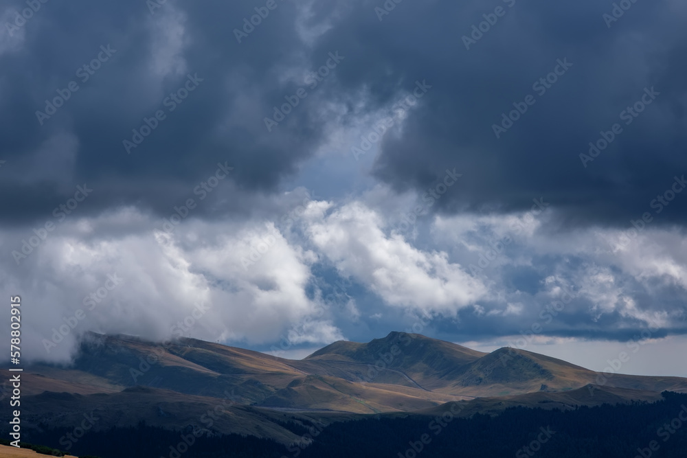 Beautiful aerial panoramic view of the Bucegi mountains (Brasov, Romania) alpine grassy plateaus, after a late summer storm, the sky is covered with huge fluffy clouds. Ecological awareness concept