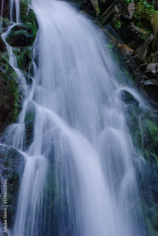 Beautiful mountain rainforest waterfall with fast flowing water and rocks, long exposure. Natural seasonal travel outdoor background with sun shining. Stream waterfall on rocks in the forest Beautiful mountain rainforest waterfall with fast flowing water and rocks, long exposure. Natural seasonal travel outdoor background with sun shining. Stream waterfall on rocks in the forest
