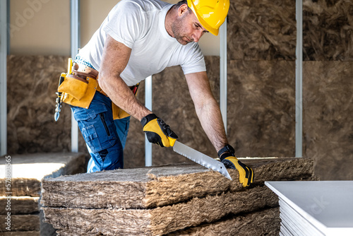 The drywaller cutting with a special knife the acoustic insulation before embed a in a plasterboard konstruksion.