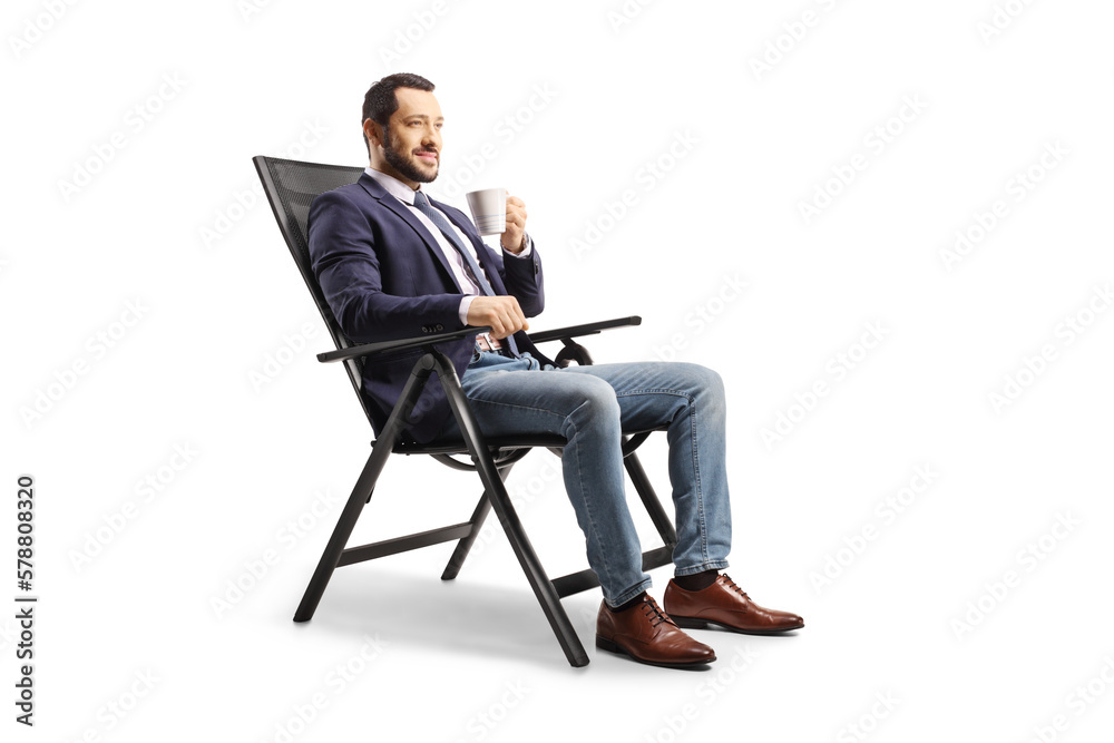 Young man resting in a foldable chair and holding a cup Young man resting in a foldable chair and holding a cup