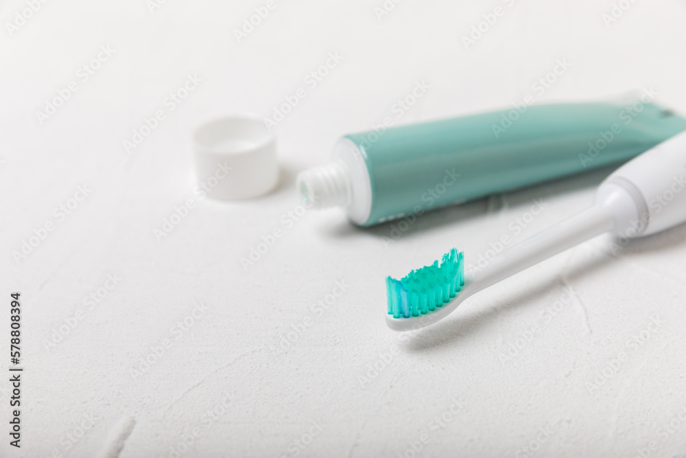 Electronic ultrasonic toothbrush and toothpaste on texture background. Items for dental care and caries prevention in the bathroom. Dentistry concept. Copy space.