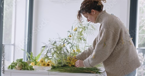 female doing new bouquet. Girl working in flower shop studio. Female florist artist cleans flowers for a beautiful bouquet, workplace view. High quality 4k footage
