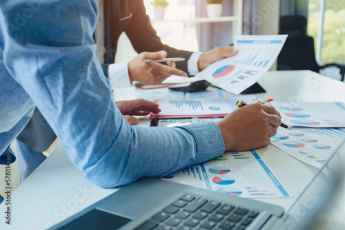 Business people analyzing investment graphs, brainstorming meeting and discussing plans in conference room. Using graph sheets, laptops and calculators business and investment ideas