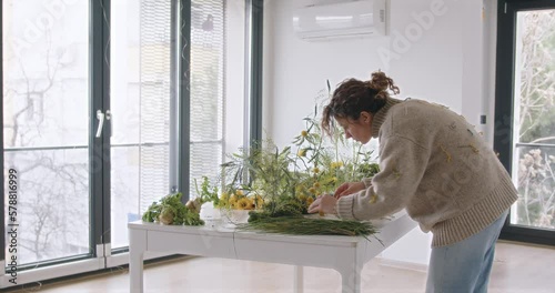 female doing new bouquet. Girl working in flower shop studio. Female florist artist cleans flowers for a beautiful bouquet, workplace view. High quality 4k footage