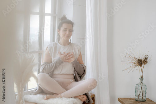 Zufriedene Frau sitzt dankbar am Fenster photo