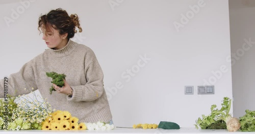 female doing new bouquet. Girl working in flower shop studio. Female florist artist cleans flowers for a beautiful bouquet, workplace view. High quality 4k footage