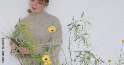 female doing new bouquet. Girl working in flower shop studio. Female florist artist cleans flowers for a beautiful bouquet, workplace view. High quality 4k footage