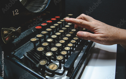Woman's hands typing on a vintage typewriter detail, interesting object, mix of art, culture and historical engineering.